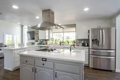 a kitchen with white cabinets and a stainless steel refrigerator at Casa Rosé in Temecula