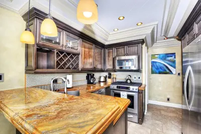 a kitchen with wooden cabinets and a marble counter top at Villa Bella Mare at the Retreat in Laguna Beach in Laguna Beach