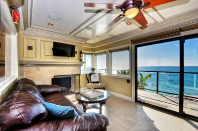 a living room with a leather couch and a fireplace at Villa Bella Mare at the Retreat in Laguna Beach in Laguna Beach