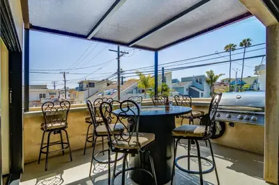a balcony with a table and chairs and a grill at 209 9th St in Newport Beach