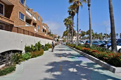 a man riding a bike down a sidewalk next to a building at 600 E Oceanfront 2B in Newport Beach