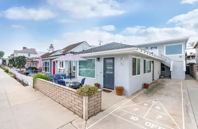 a white house with a blue door on a street at 129 Opal Ave A & B in Newport Beach