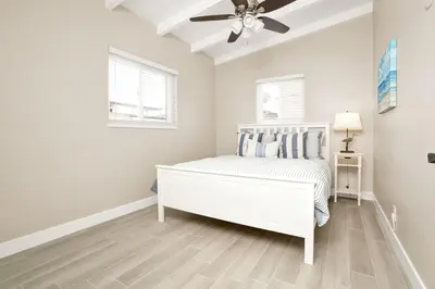 a white bedroom with a bed and a ceiling fan at 114 Forty Second Street B in Newport Beach