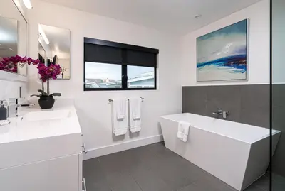 a white bathroom with a tub and a sink at Pier to Pier in Newport Beach