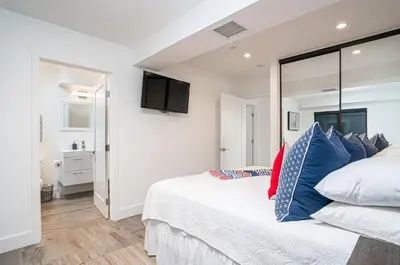 a white bedroom with a large bed with blue pillows at Pier to Pier in Newport Beach