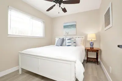a bedroom with a white bed and a ceiling fan at 114 Forty-Second Street A in Newport Beach