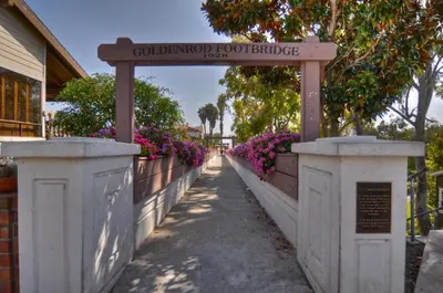 a sign on a fence with purple flowers at 310 and a half Iris Ave in Newport Beach