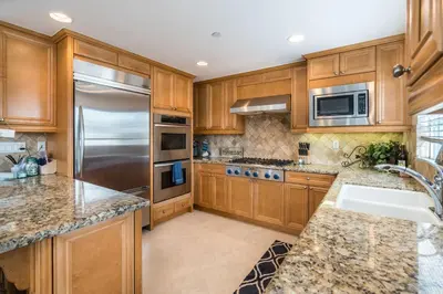 a kitchen with wooden cabinets and a stainless steel refrigerator at 310 and a half Iris Ave in Newport Beach