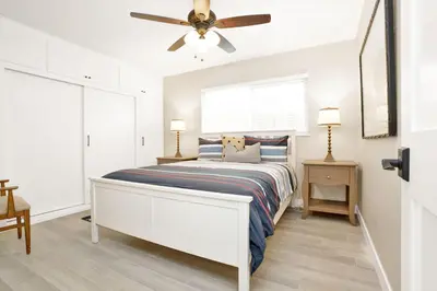 a white bedroom with a bed and a ceiling fan at 114 Forty Second Street A and B in Newport Beach