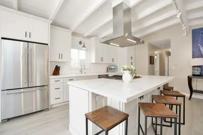 a kitchen with white cabinets and a large island with stools at 114 Forty Second Street A and B in Newport Beach
