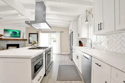 a white kitchen with white cabinets and a fireplace at 114 Forty Second Street A and B in Newport Beach