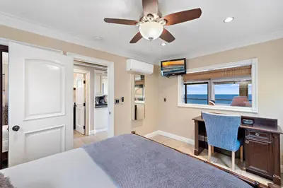 a bedroom with a bed and a desk and a ceiling fan at Villa Leone at the Retreat in Laguna Beach in Laguna Beach