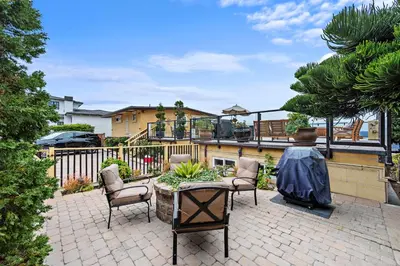 a patio with chairs and a table and a balcony at Villa Palazzo D'Stella at the Retreat in Laguna Beach