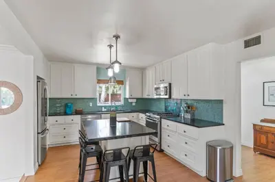 a kitchen with white cabinets and a black counter top at Luxury Beach House. Pool/Hot Tub! Walk to Beach! in Carlsbad