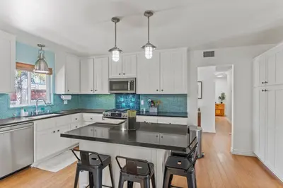 a kitchen with white cabinets and a black counter top at Luxury Beach House. Pool/Hot Tub! Walk to Beach! in Carlsbad
