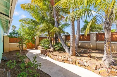 a garden with palm trees and a stone wall at Luxury Beach House. Pool/Hot Tub! Walk to Beach! in Carlsbad