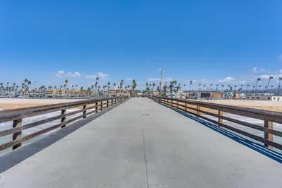 a boardwalk at the beach with palm trees and a blue sky at Newport Beach Vacation Rental Steps to Shore! in Newport Beach