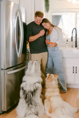 a man and a woman in a kitchen with two cats at Luxe OB Home, Walk to Beach, Sauna, and Backyard in San Diego