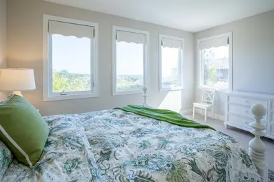 a bedroom with a bed and three windows at Escape to Luxury Newport Coast Pelican Gated Home in Newport Beach