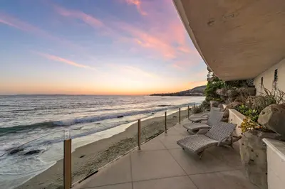 a patio with chairs on the beach at sunset at Laguna Villa in Laguna Beach