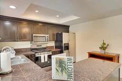 a kitchen with wooden cabinets and a stainless steel refrigerator at Sunny Vista Vacation Rental Home 12 Mi to Beach! in Vista