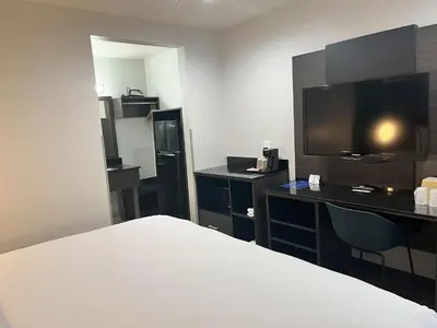 a hotel room with a bed and a desk and a tv at Suites Escondido CA in Escondido
