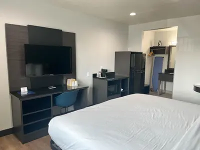 a hotel room with a bed and a desk with a television at Suites Escondido CA in Escondido
