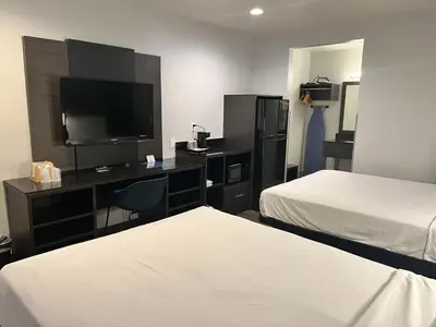 a hotel room with two beds and a desk with a television at Suites Escondido CA in Escondido