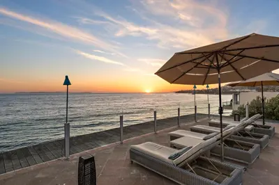 a group of lounge chairs and umbrellas on the beach at Villa Calypso in Laguna Beach