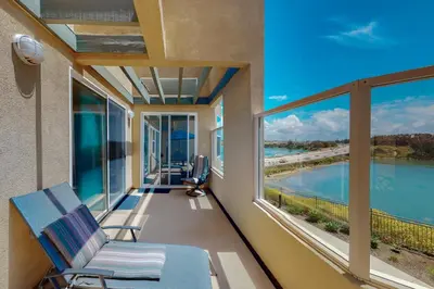 a balcony with a chair and a view of the water at Lagoon Sunrise 205 - 30-Night Minimum in Carlsbad