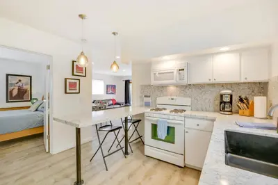 a kitchen with white cabinets and a bed in a room at San Diego Home with Deck Walk to Mission Beach! in San Diego